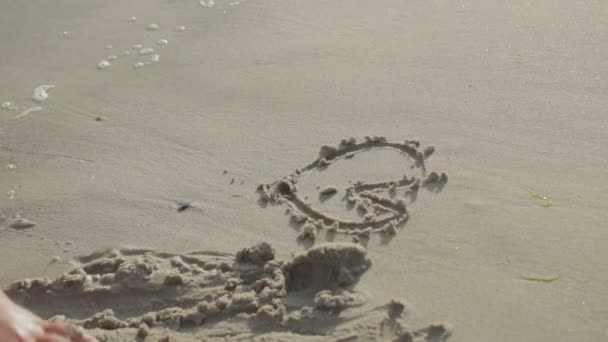 Meisje trekt een figuren in het zand op de beachbeaches — Stockvideo