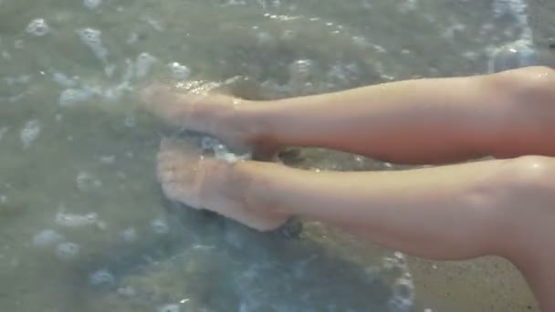 Tanned legs of a young girl splashing in the sea — Stock Video