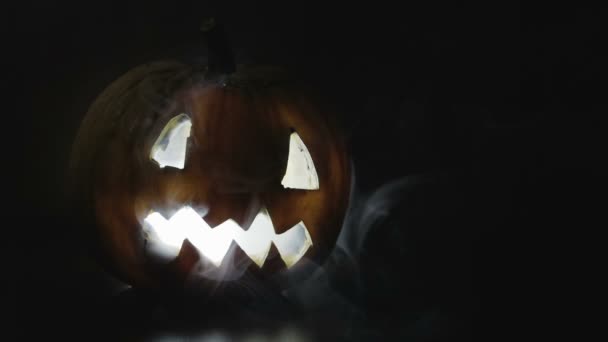 Жуткая, страшная вырезанная тыква на Хэллоуин в дыму — стоковое видео