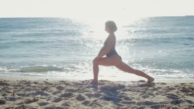 Genç kız plajda denizin kenarında Fitness yapıyor
