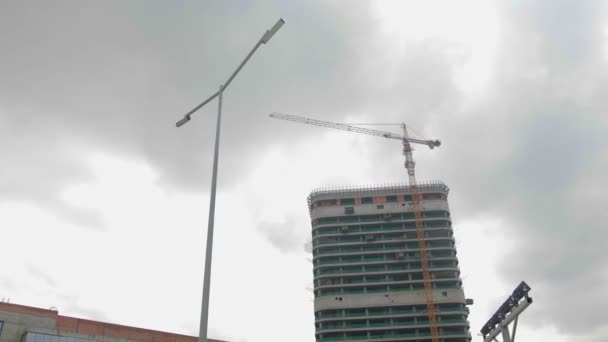 Crane works on the construction site against the background of a high-rise building — Stock Video