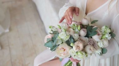 Sabah yeni evliler. Genç gelin beyaz bir sabahlık içinde inceler ve yatağa oturmuş düğün buket dokunur