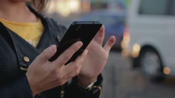Портрет молодой девушки, которая стоит в городе, в ее руках смартфон, мобильный телефон — стоковое видео