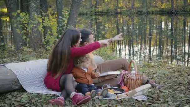 Família feliz no piquenique perto do lago na floresta — Vídeo de Stock