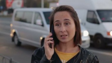 Şehir gürültüsünden, bokeh arka plan üzerinde bir cep telefonu konuşurken genç kız