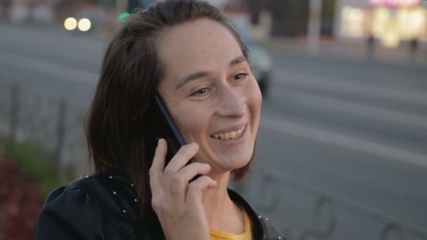 Chica joven hablando en un teléfono móvil en el fondo del bullicio de la ciudad, bokeh — Vídeos de Stock