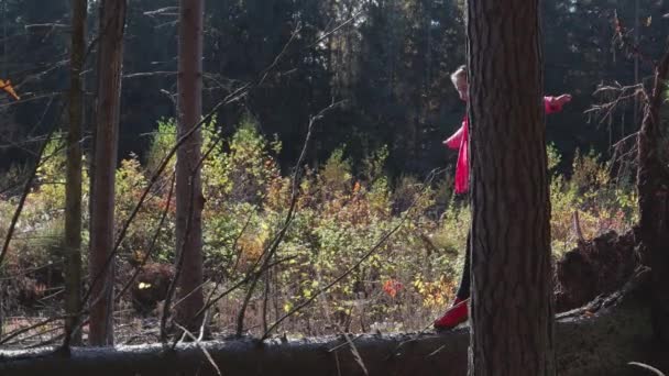 Молодая деревенская девушка идет по бревну, против осеннего леса — стоковое видео