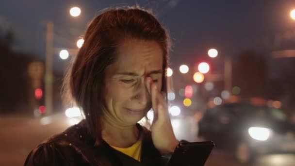 Emocionada, jovencita hablando por teléfono y llorando en la ciudad nocturna — Vídeo de stock