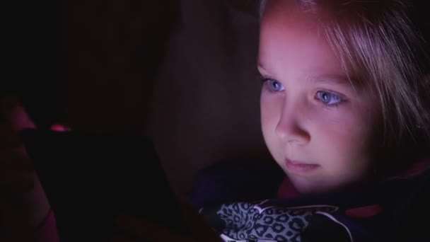Liten flicka som leker tablett, telefon på natten, närbild — Stockvideo