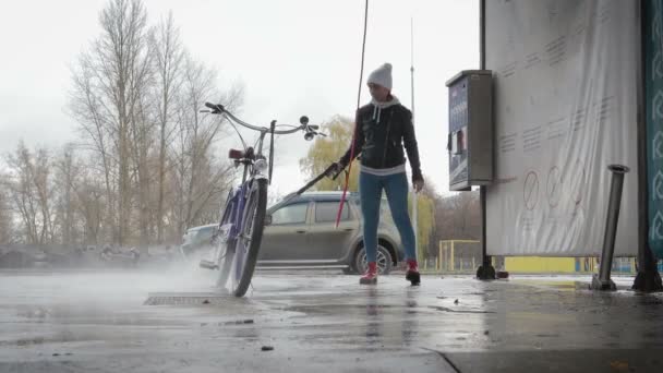 Ung flicka tvättar sin cykel på biltvätten — Stockvideo