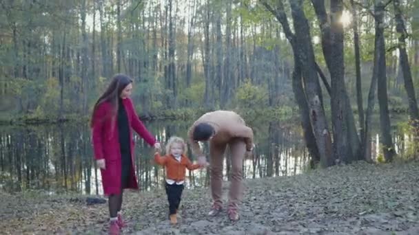 Ung, lycklig familj promenader nära sjön i höst. Familjebegreppet — Stockvideo