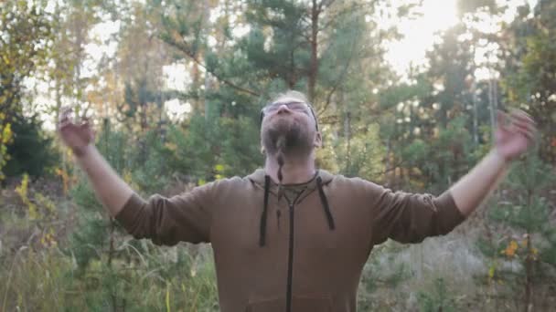 Ellerini gökyüzüne kadar büyüten sakalı olan genç bir adam portresi. Sevinç ve mutluluk kavramı — Stok video