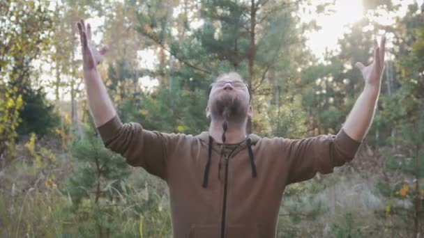 Portréja egy fiatal férfi szakáll, aki felemelte a kezét az égre. A koncepció az öröm és boldogság — Stock videók