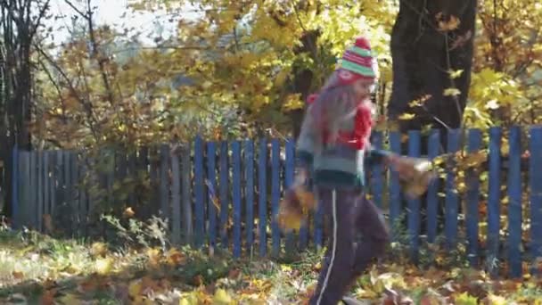 Веселі діти розважаються, граючи і стрибаючи з кленовим листям в осінньому парку — стокове відео