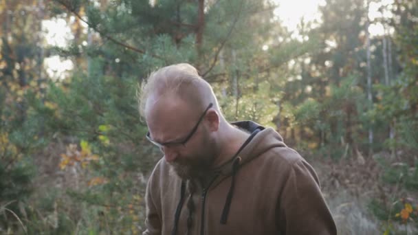 En ung man med ett skägg som letar en mobiltelefon signal i skogen — Stockvideo