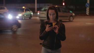 Çekici kız bir telefon gece şehir ışıkları ve araçların arka plan üzerinde tutarak