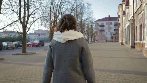 Eine Frau im Mantel in der Herbst- oder Frühlingsstadt — Stockvideo