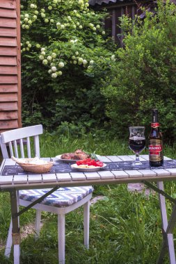 14 Haziran 2020 St. Petersburg Rusya. Barbekü ve birayla basit bir akşam yemeği. Bahçesinde çiçek açan ağaçların arkasında Krushovitsa ekmek ve domatesleri var..
