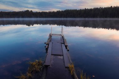 Sabah sisi olan bir orman gölünde eski bir tekne iskelesi. Kuzey yaz manzarası