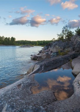 Karelia 'da Ladoga Gölü' ndeki Koyonsaari Adası yaz sabahı. Gökyüzü bir su birikintisine yansıyor Ulusal Park Ladoga Skerries 