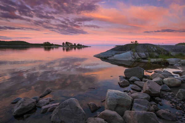 Закат на Ладожском озере в российском национальном парке "Ладожские шхеры" летом. Природный пейзаж с водными скалами, каменными островами и лесом вблизи берега
