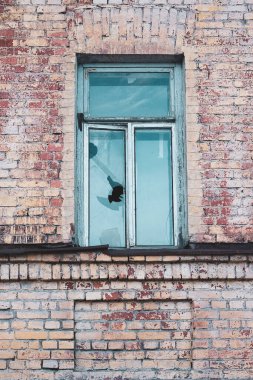 Eski bir tuğla evde kırık bir taş pencere.
