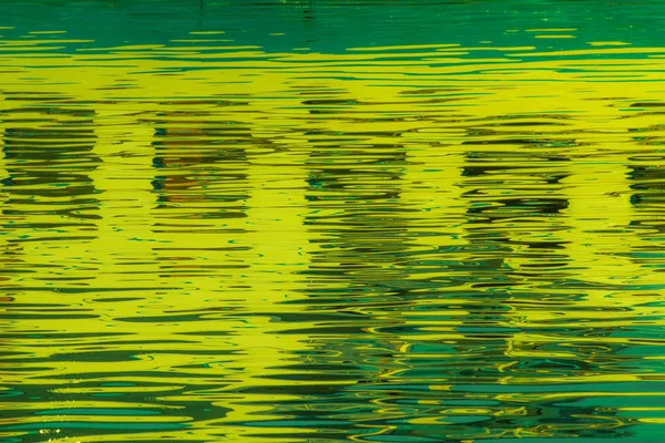 由夕阳形成不同大小和形状的微光和色彩所创造的湖泊水域中的窗户反射 — 图库照片
