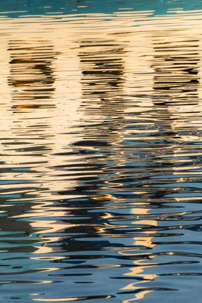 由夕阳形成不同大小和形状的微光和色彩所创造的湖泊水域中的窗户反射 — 图库照片