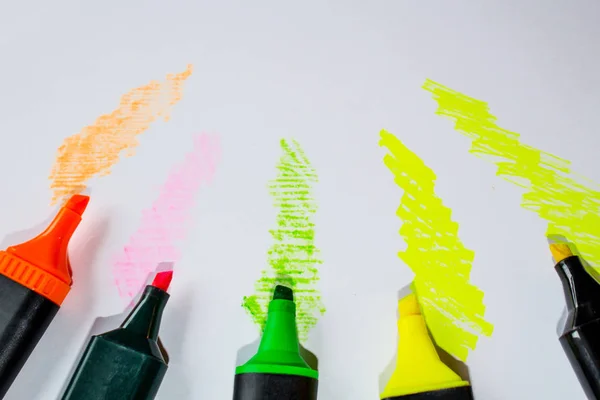 Multicolored markers on white sheet background