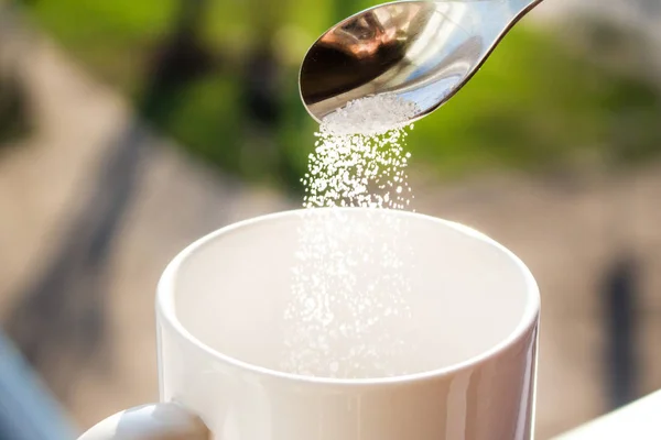 Pour sugar into a mug