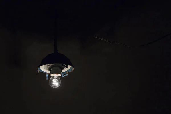 Incandescent lamp in a broken chandelier background