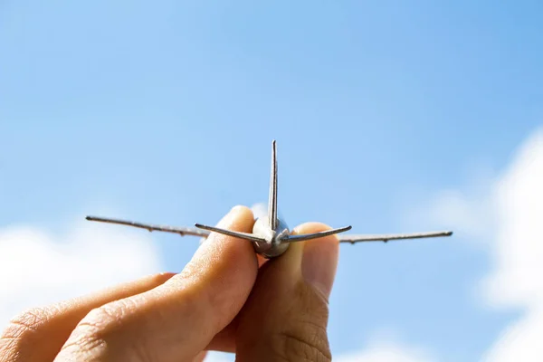 Toy airplane in hand on sky background