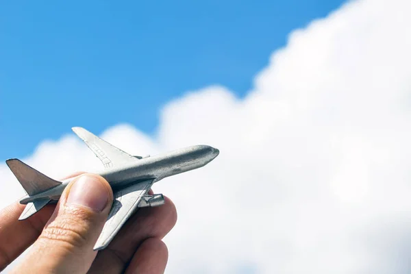 Toy airplane in hand on sky background