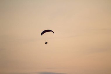 Adam bir yamaçparaşütü deniz ve plaj üzerinde uçuyor