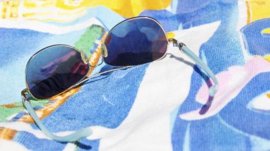 Bir havlu üzerinde sahilde güneş gözlüğü