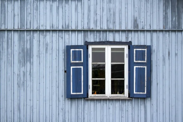 a cozy window with shutters in a blue wooden house