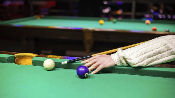 the hand of the guy playing billiards