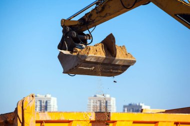 Ekskavatör bir kamyon gövdesini kuma dökülen