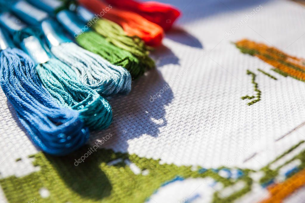multicolored threads and cross stitch
