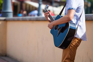 Genç adam bir akustik gitar bir şehir sokak oynarken