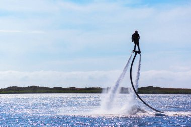 bir adam bir flyboard güneşli bir günde bir gölde biniyor