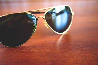 koyu yeşil ve altın moda güneş gözlüğü masada, retro tonda