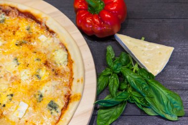 Fesleğenli dört peynir ile iştah açıcı pizza bir siyah masaya düz yatıyordu bırakır