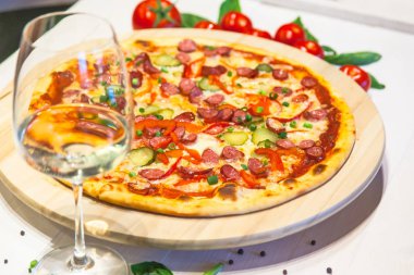 küçük sosis, fesleğen, domates ve bir bardak beyaz şarap beyaz bir tablo ile iştah açıcı pizza