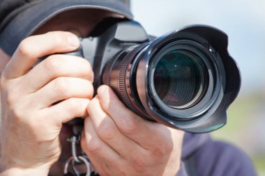 büyük bir profesyonel kamera ile erkek fotoğrafçı vizör bakar ve fotoğraf çeker