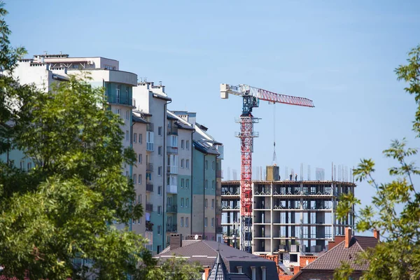 A large crane builds a new building among the houses