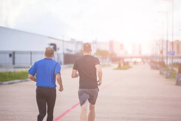 two men jogging on the track in the city, toned