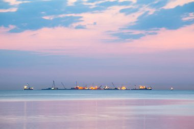 Işıkları mor alacakaranlık denizden, uzun pozlama sırasında ufukta gemilerin