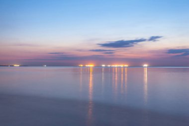 Mor alacakaranlık pürüzsüz deniz yüzey uzun pozlama ve ışık ufukta bir gemi