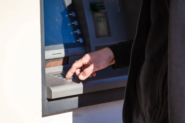 close-up of the hand of a person withdrawing money from an ATM